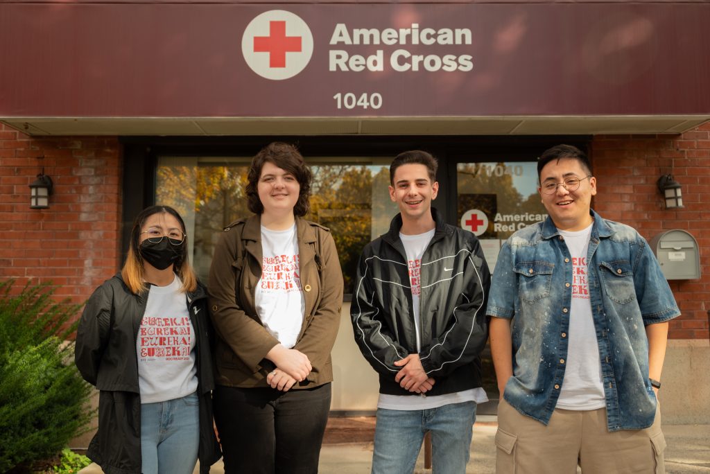 4 individuals standing on front of the American Red Cross logo
